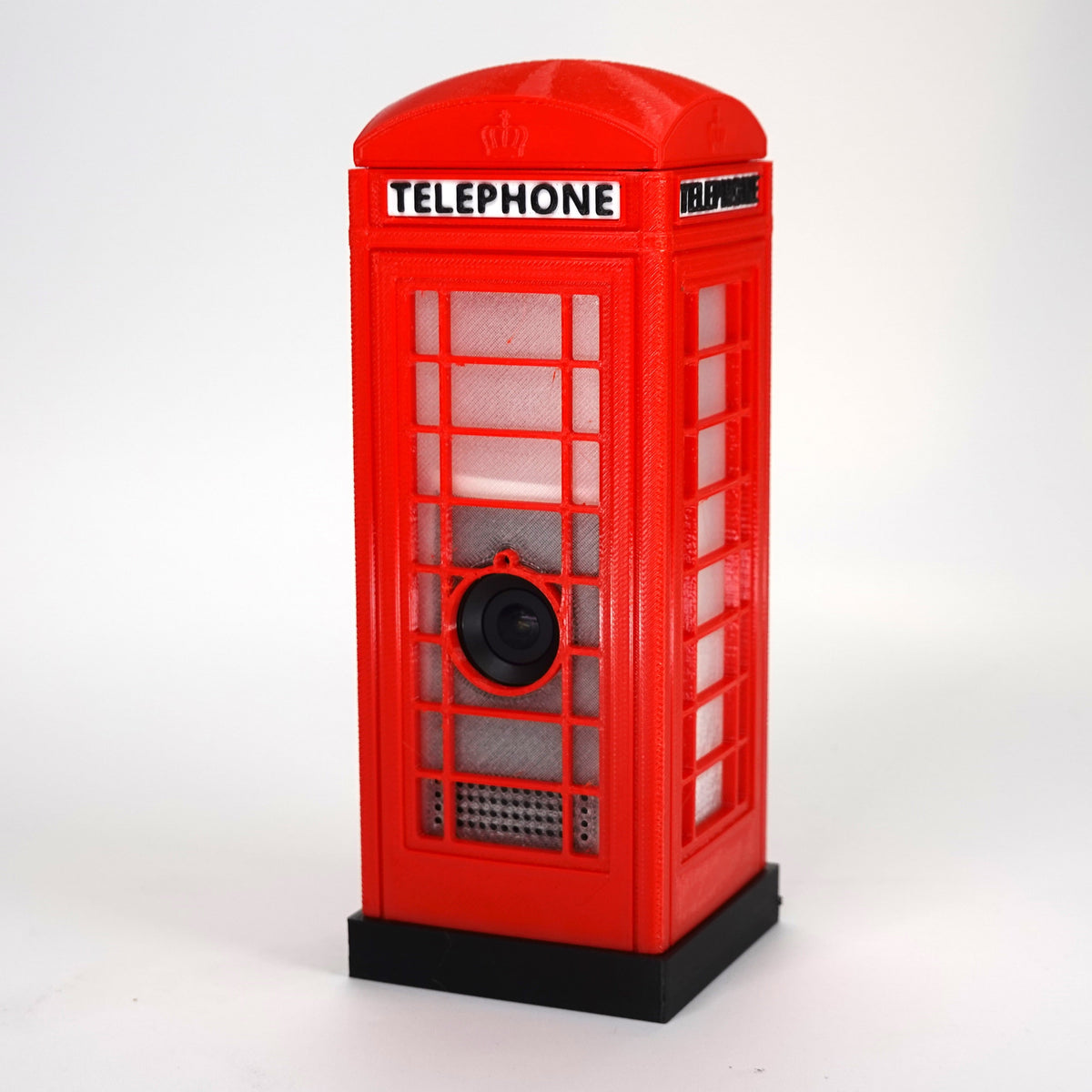 Front-facing view of a red 3D-printed miniature London K6 telephone box decorative case designed to hide a Ring Indoor Cam 2K.